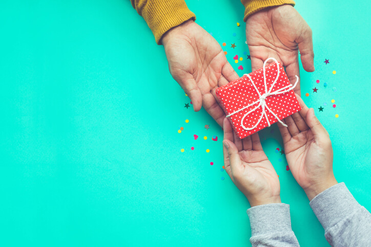 Two people sharing a gift on a turquoise background